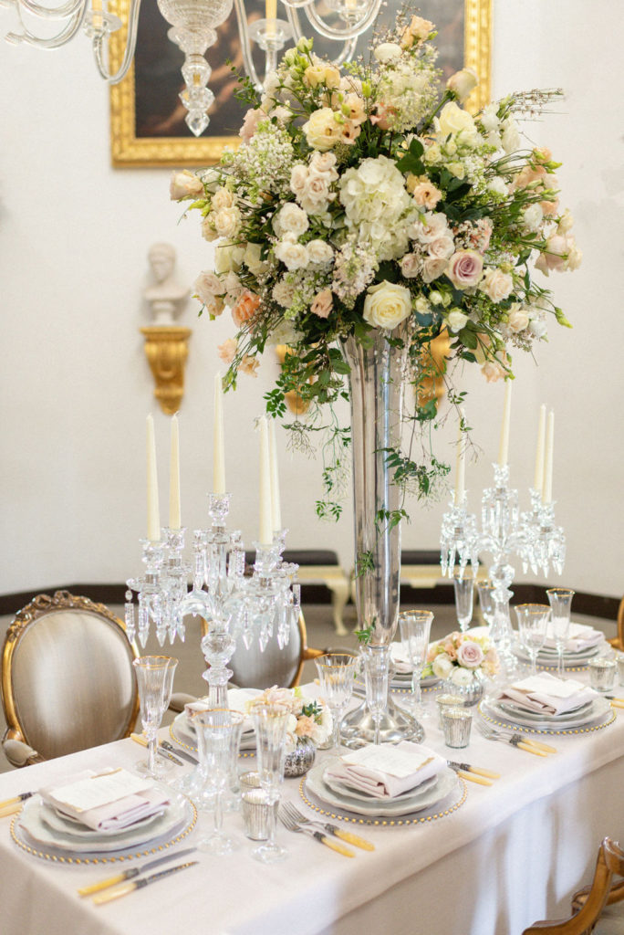 Long wedding table with tall flower centrepiece and chandelier candles