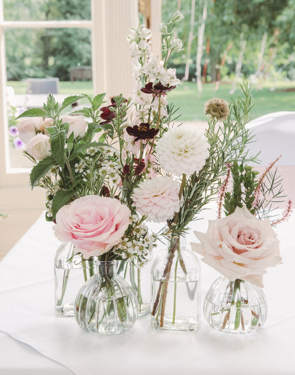 Bud vases with pale pink roses, dahlias and greenery