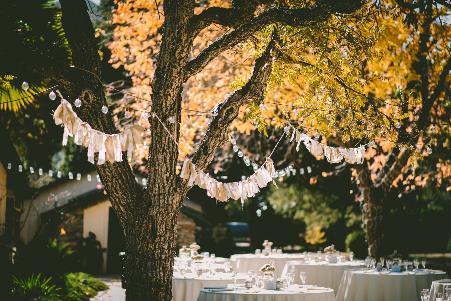 Outdoor wedding reception using fairy lights and bunting hanging from trees for the decor