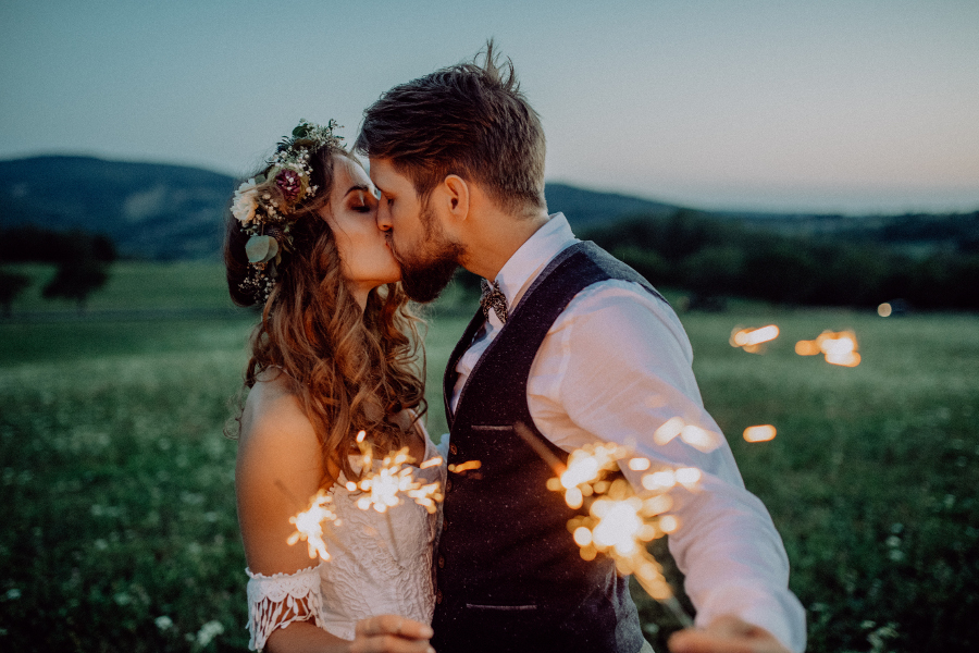 Wedding couple holding sparklers and kissing