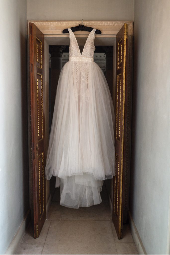Tulle and lace wedding dress hanging from doorway