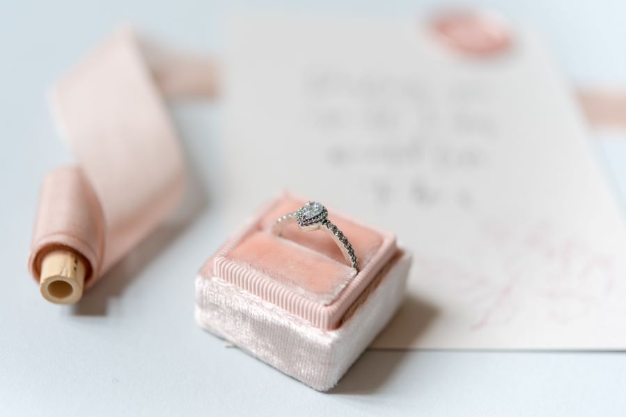 Engagement ring, ribbon and wedding stationery in blush
