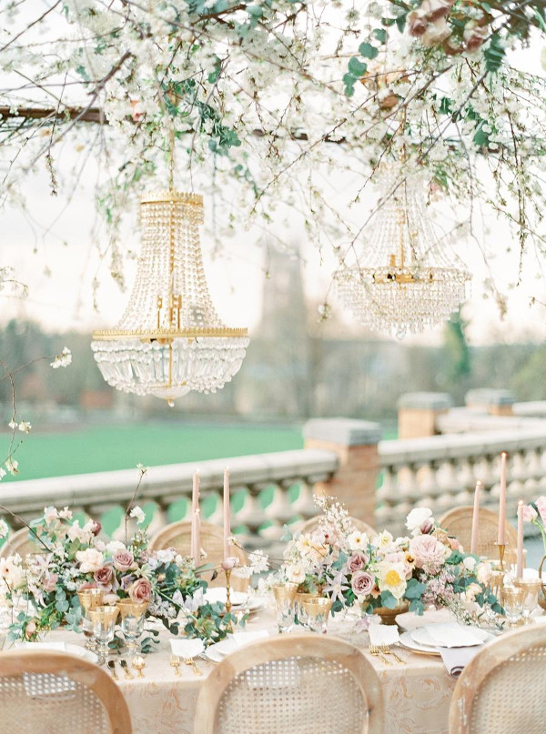 Wedding table outside with chandeliers hanging over table