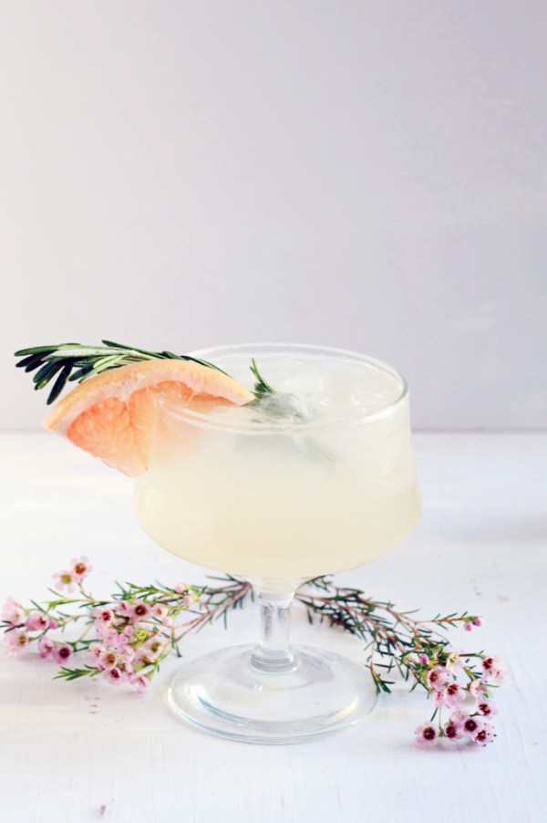 Cocktail in coupe glass with orange and rosemary garnish