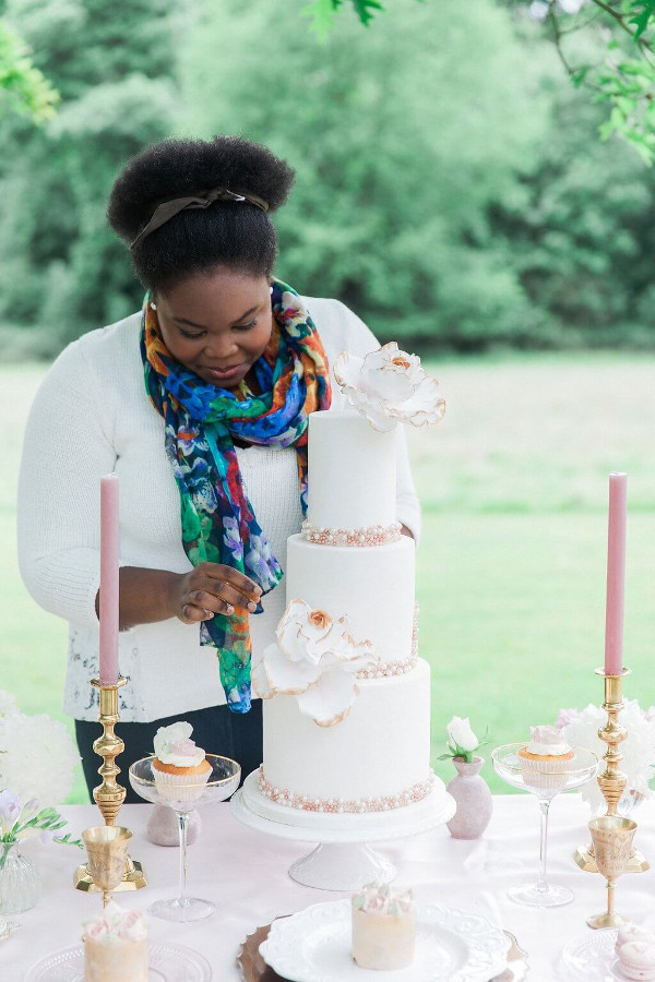 Fen from MonAnnie Cakes putting the final touches to a 3 tier wedding cake decorated with flowers