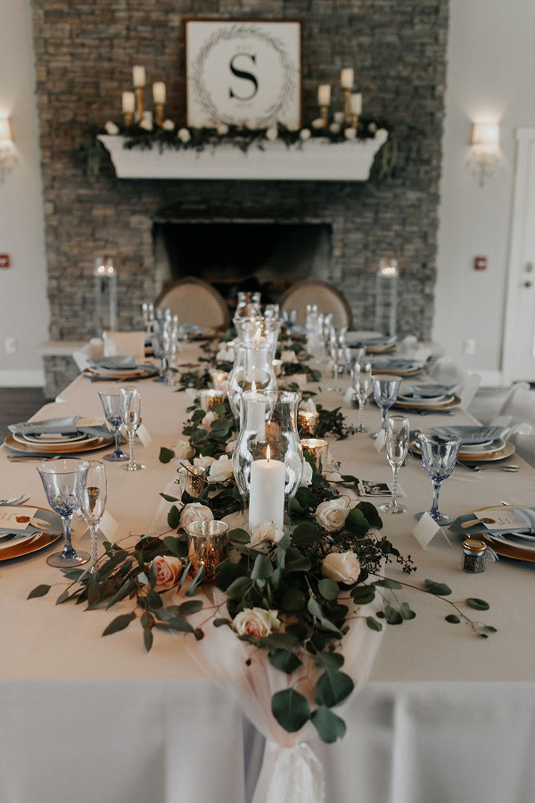 Wedding table with greenery centrepiece, candles and dark linens