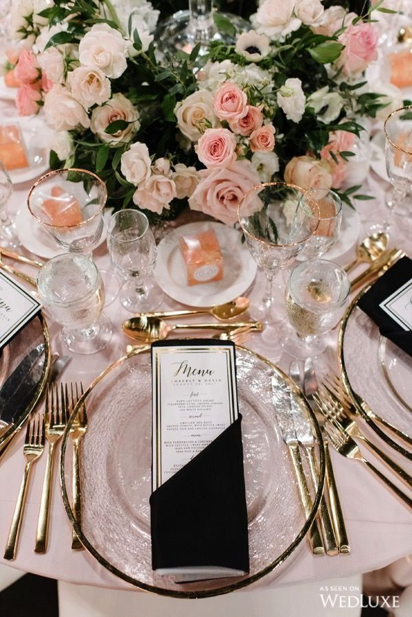 Luxurious tablescape with gold cutlery, glass chargers and dark napkins.  A floral centrepiece of blush, pale pink and burgundy roses