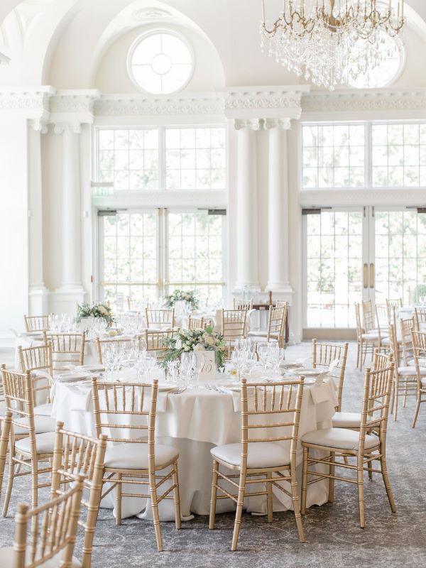 Ballroom with wedding reception tablet up with white linen, chiavari chairs and floral centrepieces