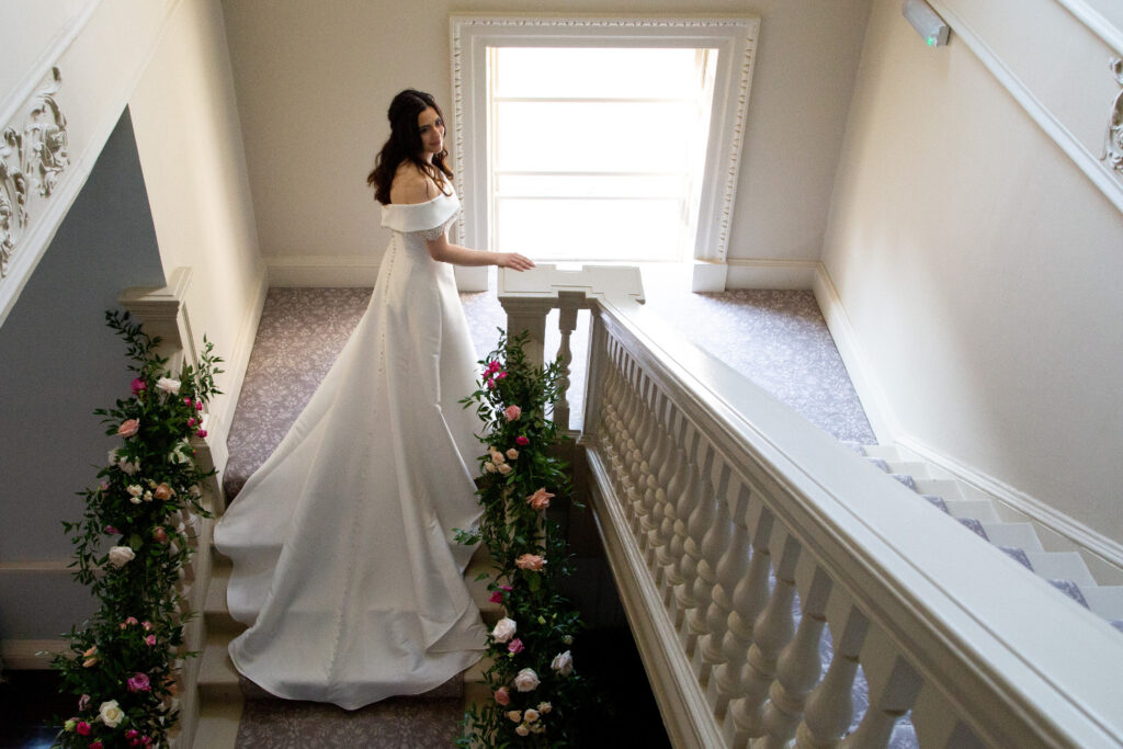 Bride standing on flowered staircase at Morden Hall