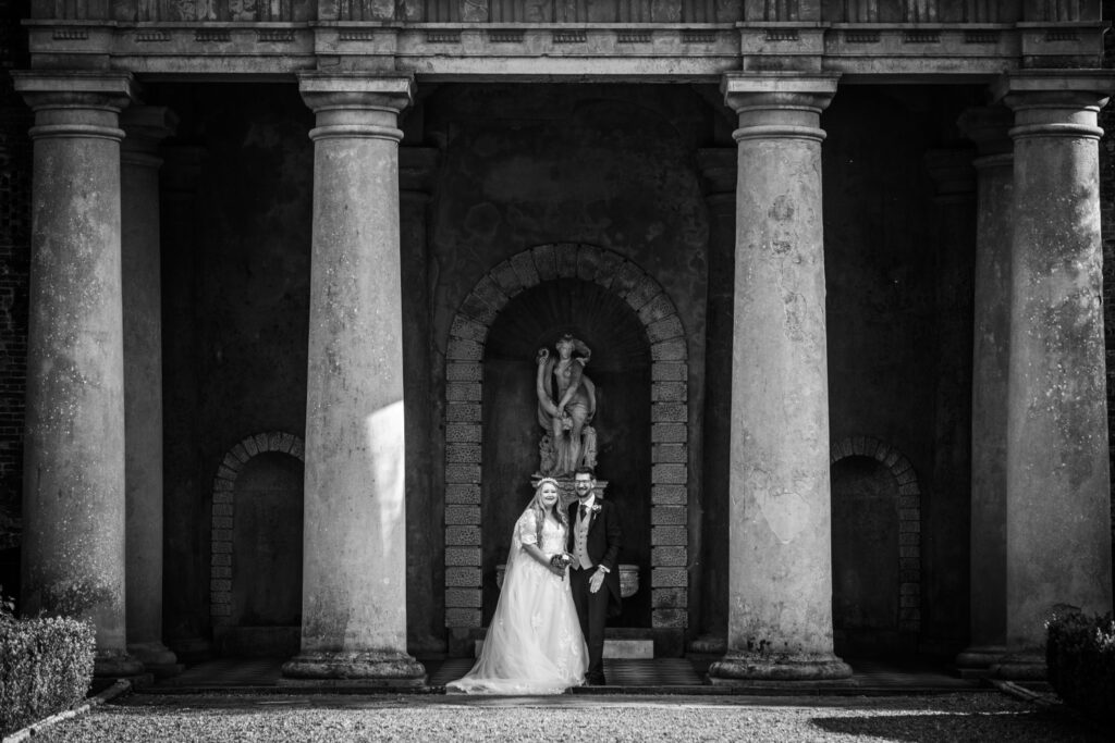 Bride and groom standing in Italian temple at Wotton House