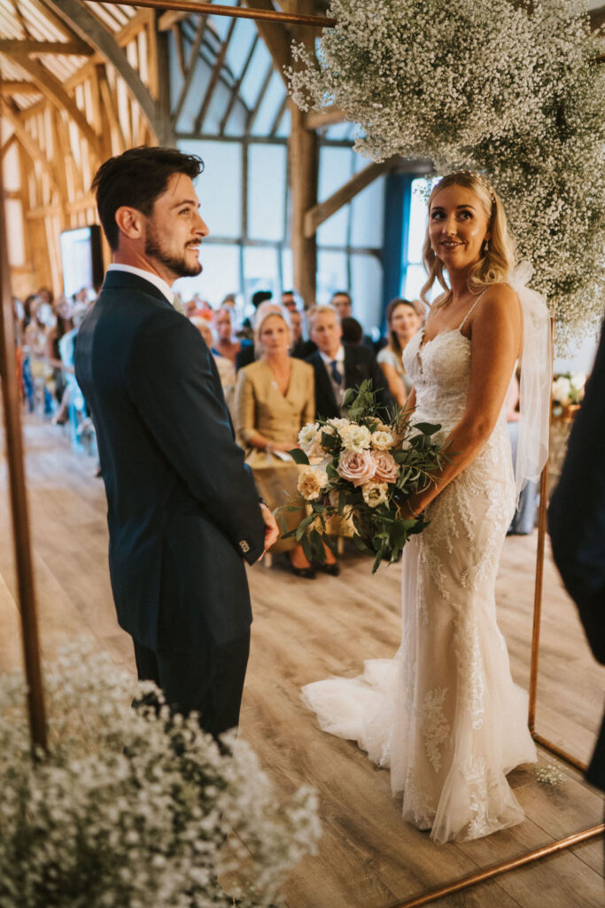 Bride and groom wedding ceremony in barn with gyposphilia and metal frame arch