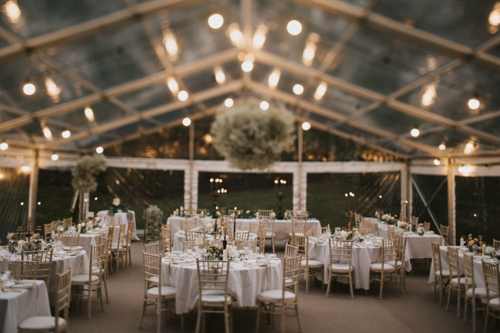 Marquee with round tables and green candles.