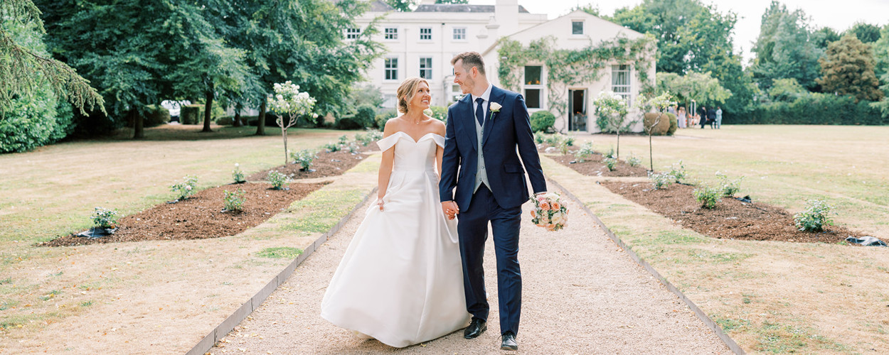 Bride and groom holding wedding bouquet on Morden Hall lawn