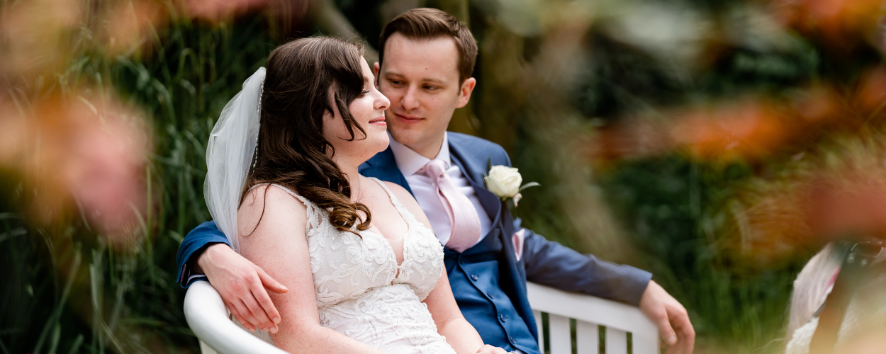 Bride and groom sitting on bench at Morden Hall