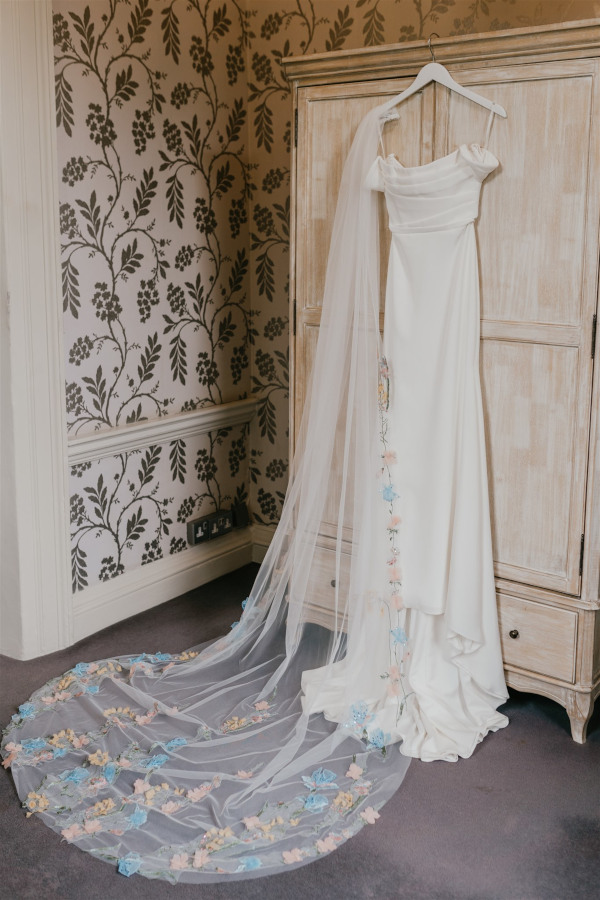 Alena Leena wedding dress and hand embroidered veil hanging off wardrobe