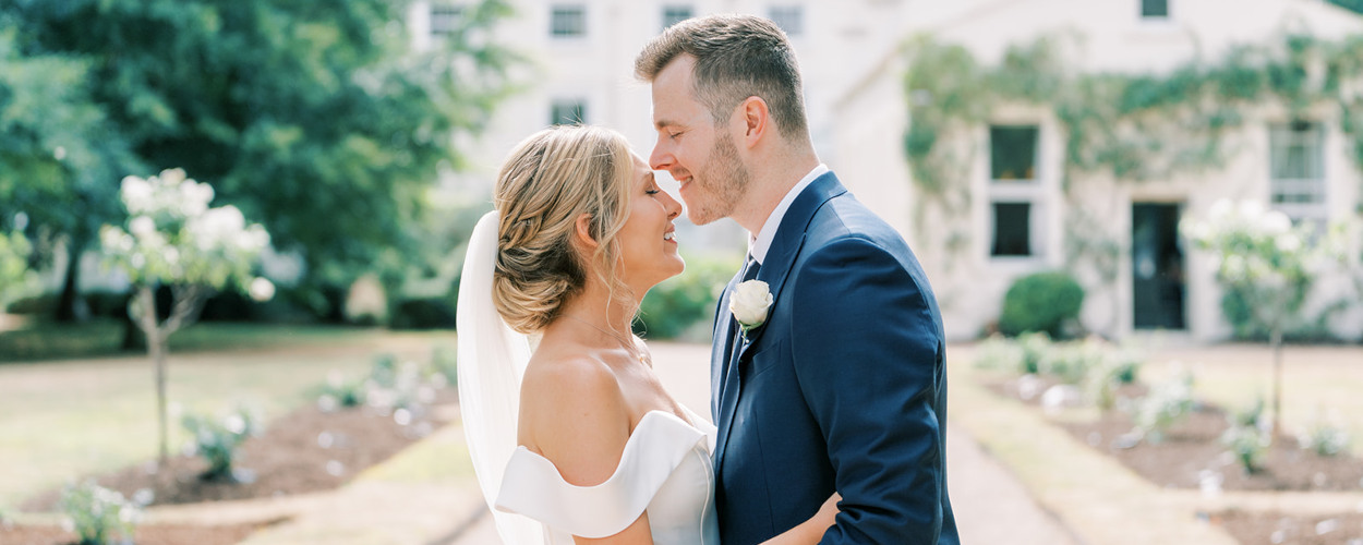 Bride and groom embracing outside Morden Hall