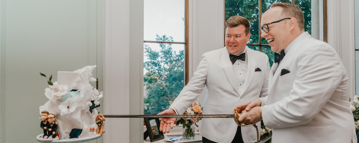 Grooms cutting wedding cake with sword