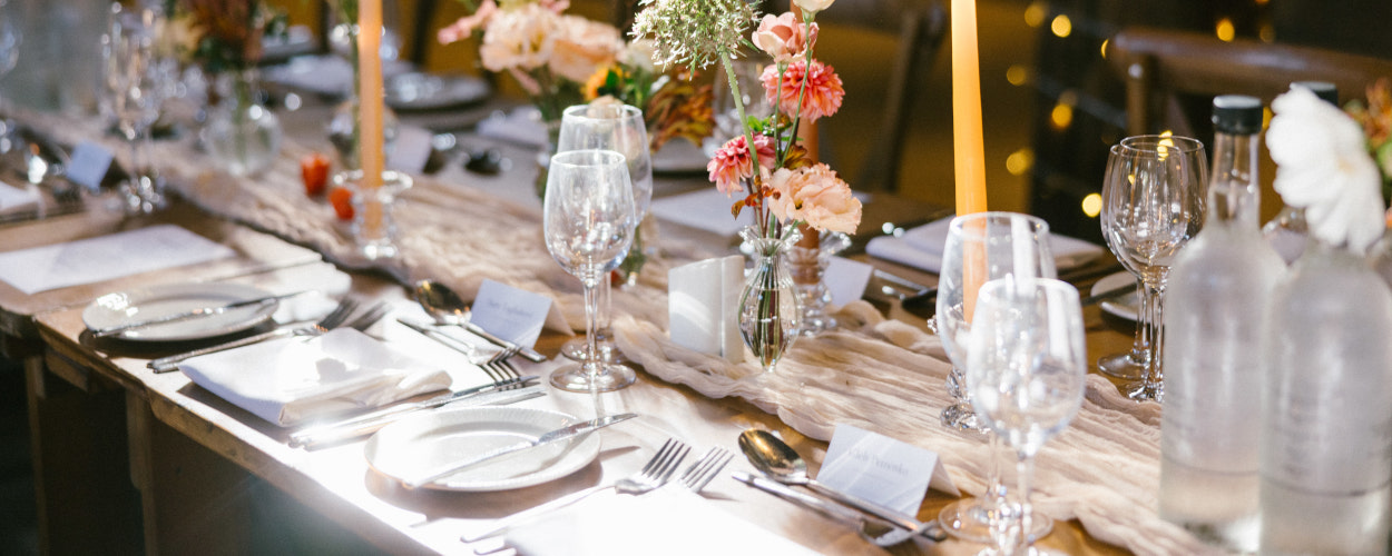 Long dining tables for wedding reception decorated with floweers and candles in autumnal colours