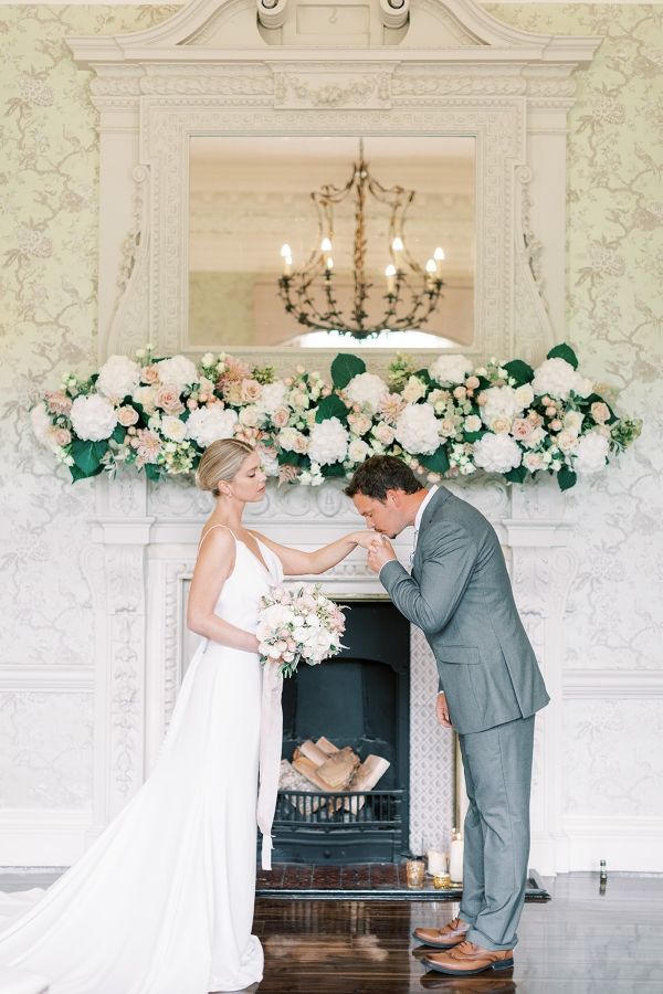 indoor wedding ceremony at morden hall with flower installation on mantlepiece and bride and groom