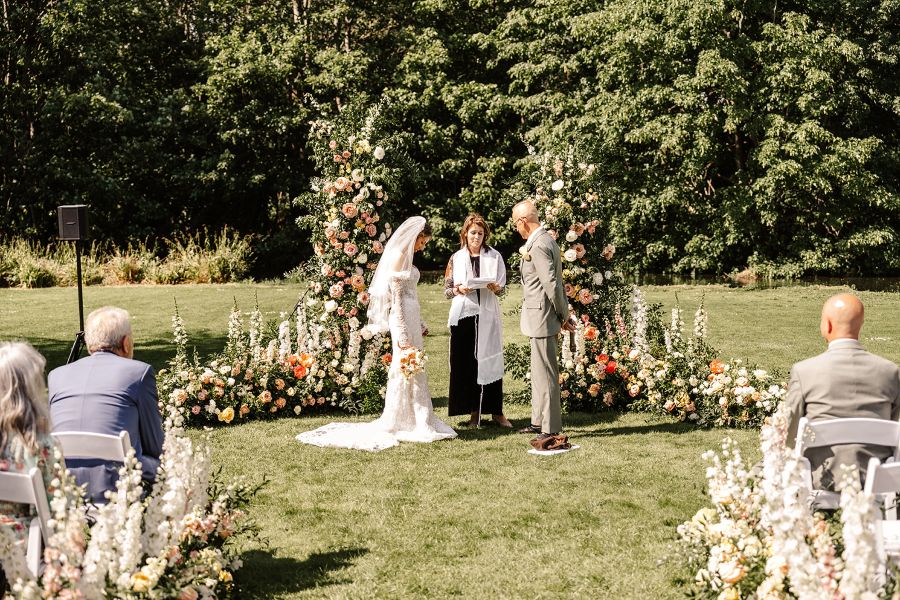 Jewish outdoor ceremony in front of semi circle flower installation at Mordne Hall