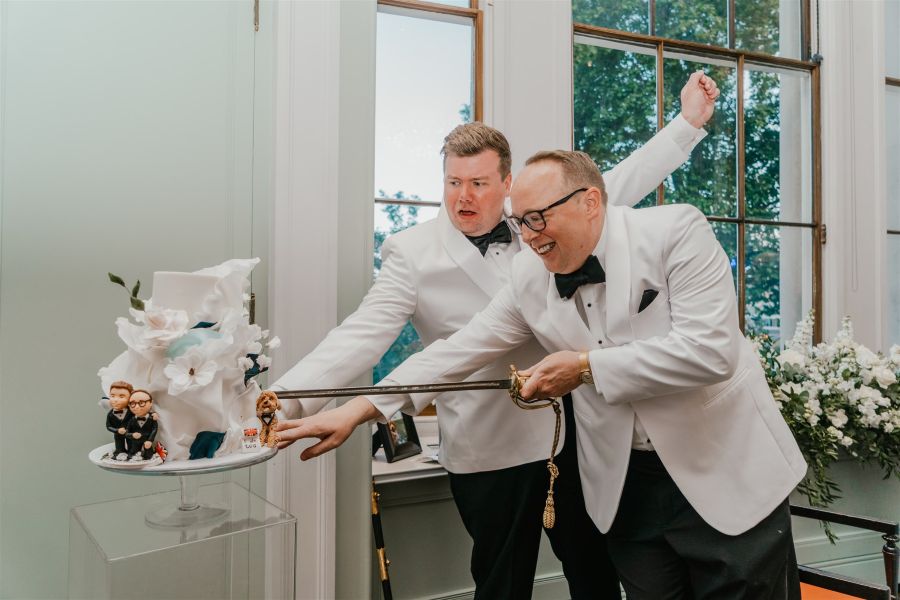 Couple cutting 3 tier cake with sword